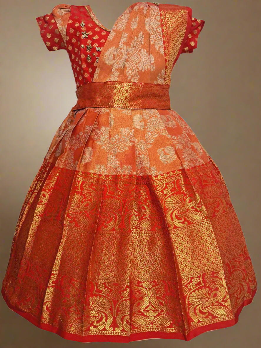 Elegant red and orange brocade long gown for girls with detachable half saree, kundan stone embellishments on top, and soft cotton lining – traditional ethnic kids wear ideal for weddings, temple visits, and South Indian festive occasions.