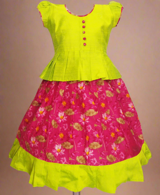 Girls Kalamkari cotton Pattu Pavadai with Ranipink floral skirt and lime green ruffle border, paired with a lime green peplum blouse enhanced with Potli buttons.
