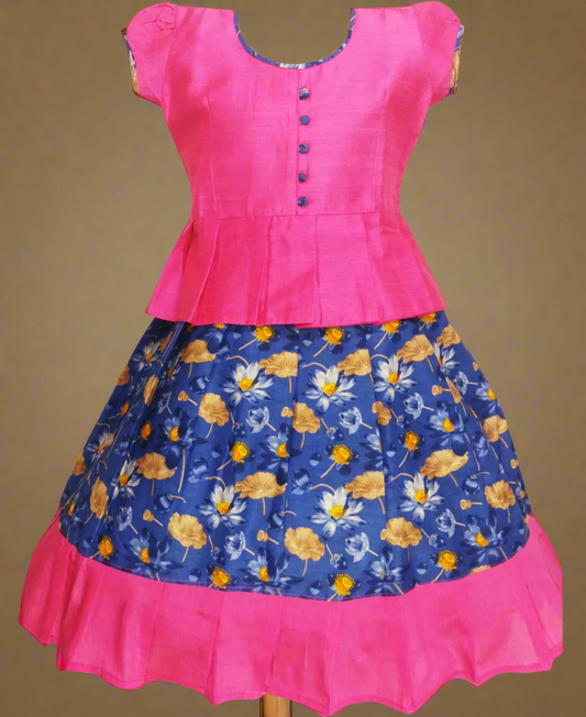 Girls Kalamkari cotton Pattu Pavadai with Blue floral skirt and Pink ruffle border, paired with a Pink peplum blouse enhanced with Potli buttons