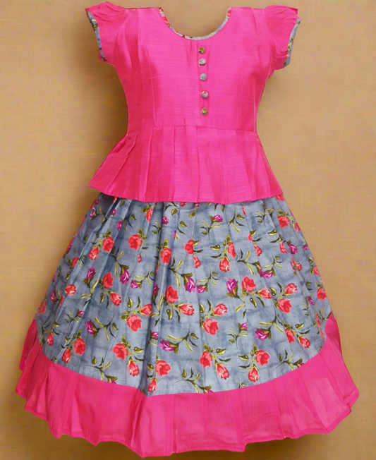 Girls Kalamkari cotton Pattu Pavadai with Grey floral skirt and Pink ruffle border, paired with a Pink peplum blouse enhanced with Potli buttons